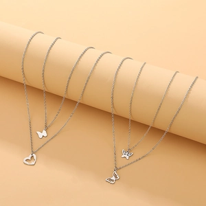 Detail of silver stainless steel butterfly and heart pendant necklaces on beige stand