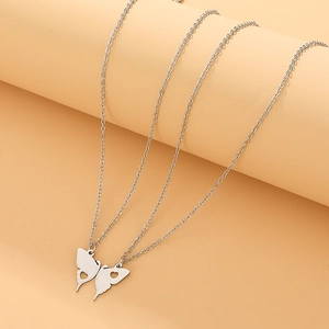 Close-up of split butterfly wing necklaces with heart cut-outs on a wavy background