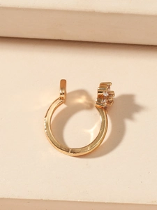 Vista detallada del brazalete dorado en forma de U con incrustaciones de circonitas