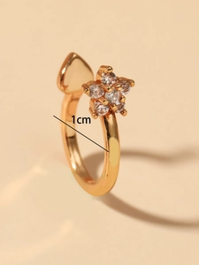 Detalle de anillo de flor dorado con circonitas mostrando medida de 1cm de diámetro