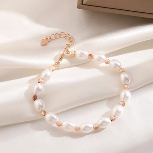 Detail of baroque pearl bracelet with rose gold beads and heart charm on silk