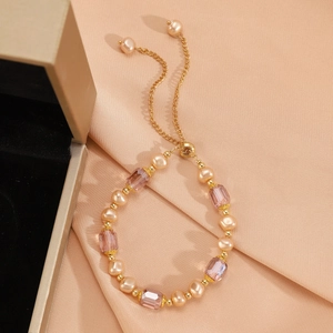 Detail of elegant gold bracelet featuring pink pearls and purple crystal rectangular beads