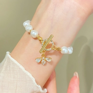 Detail of baroque pearl bracelet featuring a gold bee charm and crystal toggle closure