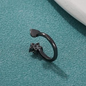Detalle de anillo ajustable negro con corazón y flor de cristal sobre fondo azulado