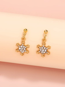 Detalle de pendientes de copo de nieve dorados con brillantes piedras para estilo invernal