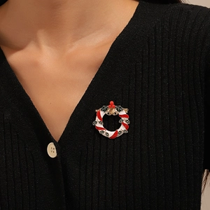 Christmas wreath brooch pin with red berries and golden bells on a black knit sweater