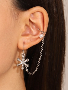 Primer plano detallado de un earcuff de copo de nieve plateado con cristales y perla blanca