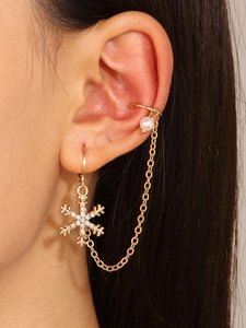 Detalle del pendiente de copo de nieve dorado con cadena y ear cuff con pedrería y perlas