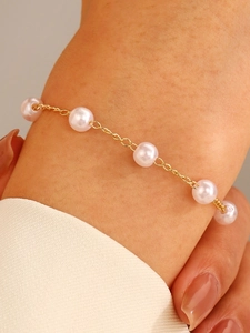 Close-up of minimalist gold link bracelet with white baroque pearls on a woman wrist