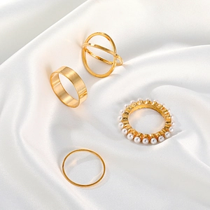 Chic 4-piece gold geometric ring set with pearls on elegant white silk background