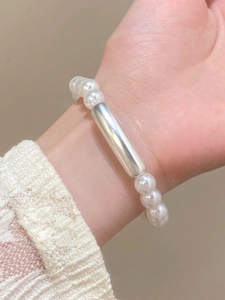 Detail of baroque pearl bracelet with silver tube accent on a lace sleeve wrist