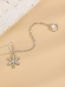 Detail of silver snowflake earring with zircons, delicate chain and pearl ear cuff