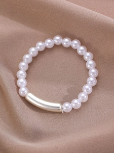 Detailed close-up of baroque pearls and curved metal tube on champagne silk fabric