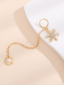 Detail of gold snowflake drop earring with white zircon, thin chain and pearl ear cuff