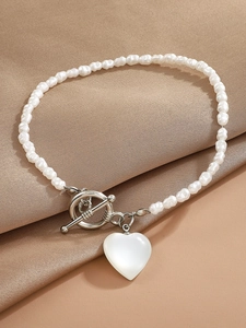 Detail of elegant baroque pearl bracelet featuring a heart pendant and metal OT toggle clasp