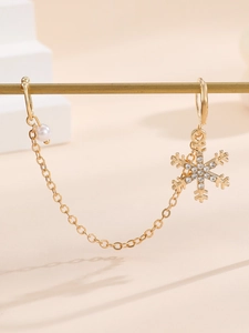 Detailed macro view of golden snowflake earrings with sparkling rhinestones and white pearl