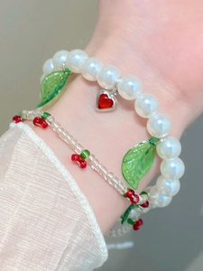 Close-up of cherry bead bracelet and pearl heart chain for women elegant jewelry set