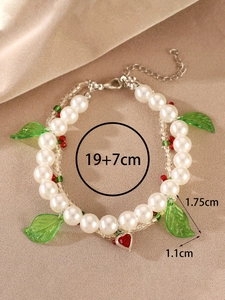 Detailed view of handmade baroque pearl bracelet with red heart and green leaf charms