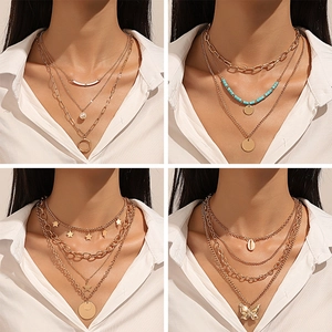 Multilayered butterfly and pearl necklaces in golden finish on a white shirt model