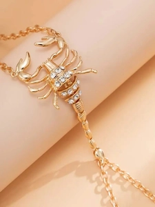 Macro detail of gold scorpion hand harness with sparkling crystals and fine chain