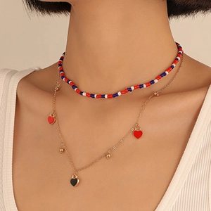 Detail van goudkleurige gelaagde ketting met kleurrijke kralen en hartvormige bedeltjes