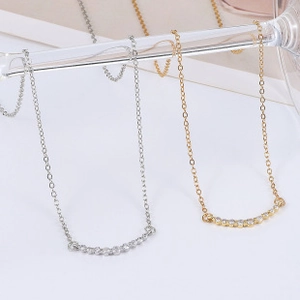 Detail of curved silver and gold necklaces with micro-pave cubic zirconia on a glass rim