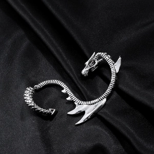 Silver dragon ear cuff earring in gothic punk style over black silk background