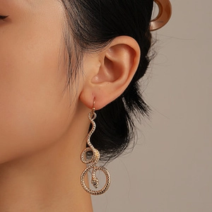 Detailansicht eines goldenen Schlangenohrrings mit Zirkonia-Inlays an einem Model