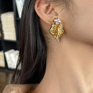 Detail of square crystal earring with irregular hammered gold texture on model