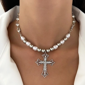 Detail of hip hop cross pendant with rhinestones and pearl chain on neck