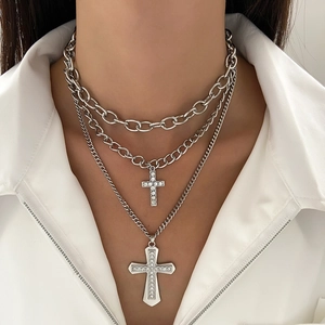 Close-up of triple-layered silver necklace with rhinestone crosses and hip-hop pendants