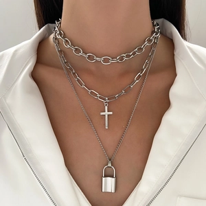 Detail showing the layered silver chain necklaces with polished cross and heart lock pendants