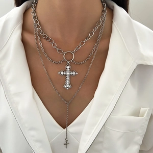 Detail of silver alloy triple layered necklace with punk cross pendants on white shirt