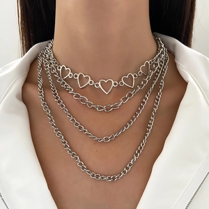 Detail of layered silver Cuban chain necklace with heart charms on model