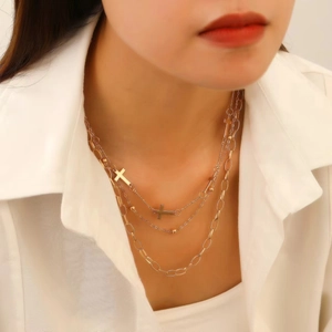 Close-up of gold layered necklace with cross pendants and bead accents on white shirt