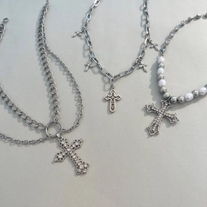 Three hip-hop style layered necklaces with rhinestone crosses and pearls on grey background