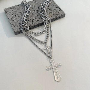 Macro shot of layered silver-tone necklaces with twin crystal-encrusted cross pendants