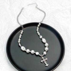 Detail of vintage silver cross pendant with rhinestones and multi-layered pearls necklace