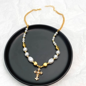Detailed macro of vintage pearl cross pendant with gold chain on a black plate