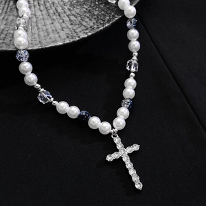 Macro shot of silver cross pendant with crystals and blue marbled pearls on necklace