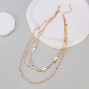 Detail view of gold layered cross necklace with polished beads and oval link chain