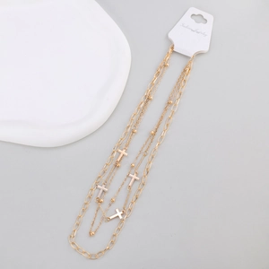 Detail of multilayered gold necklace with cross pendants and small metallic beads
