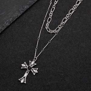 Detail of layered cross necklace with heart zircon pendant on a dark textured background