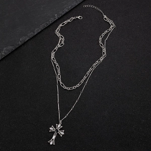 Macro detail of silver gothic cross pendant with black center stone and figaro chain