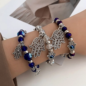 Detailed shot of Evil Eye beaded bracelet set with silver Hamsa palm charms on wrist