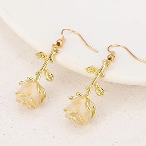 Detail of vintage gold rose earrings with beige flower buds and delicate leaf accents