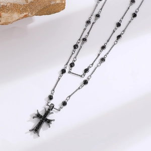 Detailed macro of layered gothic cross necklaces with black stones and antique metal finish
