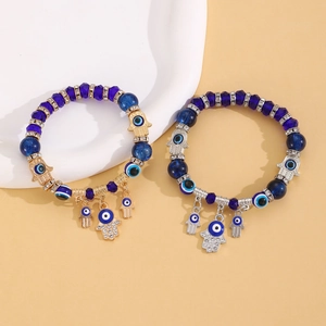 Détail de bracelets de perles bleu œil maléfique avec breloques Main de Fatma or et argent