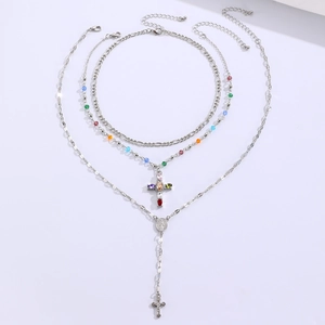 Close-up of triple-layered silver necklace with colorful bead cross and religious medals