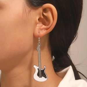 Dettaglio ravvicinato degli orecchini punk a chitarra elettrica in bianco e nero